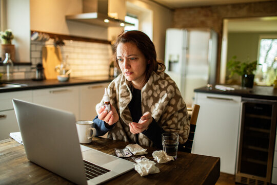 Sick woman on telehealth consultation in home kitchen