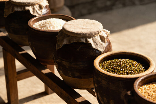 Rustic wooden shelf with ceramic jars and bowls of rice, mung beans and split peas