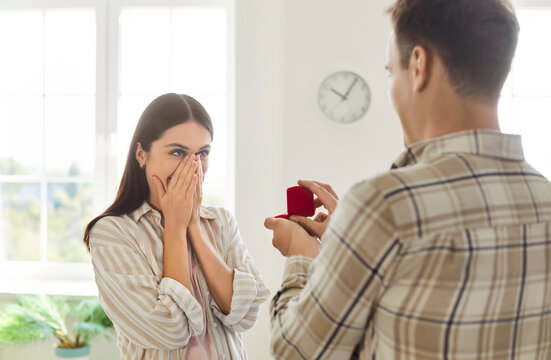 Marriage engagement ring giving and making proposal to happy girlfriend, will you marry me asking for hand surprised girlfriend covering her face in hands, lover offering romantic Valentine's day gift
