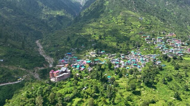 Drone pullback reveal of the sprawling off-grid settlement of Tosh nestled deep within the massive V-shaped gorge of Parvati Valley, India.