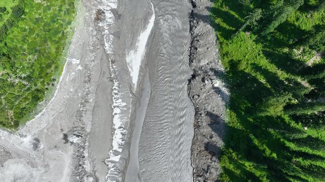 Top-down drone perspective revealing heavy sediment accumulation and washed-out riverbanks along the Parvati River gorge, highlighting alpine environmental degradation.