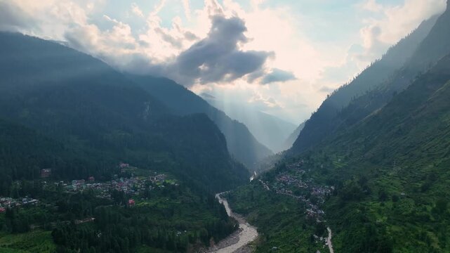 Drone shot of atmospheric crepuscular rays illuminating the rugged mountain slopes and mountain river near Tosh and Barshaini in kheerganga valley, Himachal Pradesh.