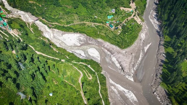 Top-down drone perspective revealing heavy sediment accumulation and washed-out riverbanks along the Parvati River gorge, highlighting alpine environmental degradation.