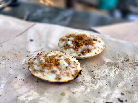 Two Freshly Prepared Traditional Indonesian Surabi Rice Flour Pancakes Topped with Savory Fermented Oncom Served on a Rustic Wooden Table