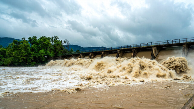 大雨後に茶色い濁流を激しく放流する河川のダム堤体（水害・防災・インフラ）