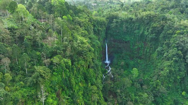 Aerial view of Kapas Biru Waterfall surrounded by dense tropical forest cliffs