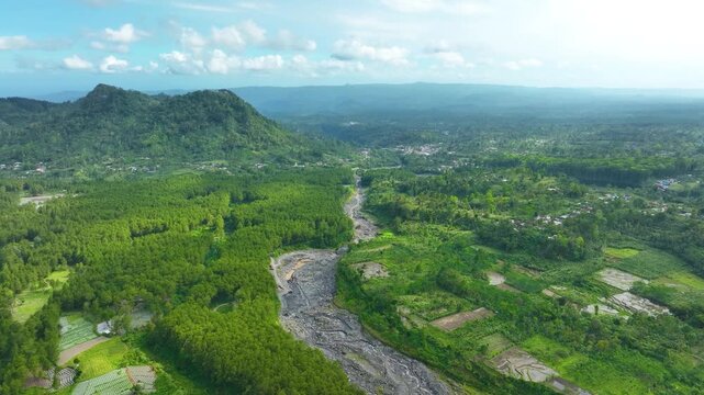 Aerial view of a solidified lava flow winding through lush green landscape near Semeru