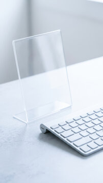 Clear acrylic display holder beside white computer keyboard on minimalist office desk