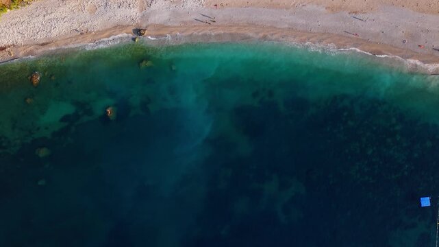 Aerial view of clear shoreline and turquoise water along a sandy beach at sunset