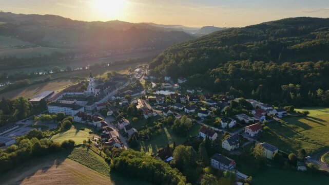 Cinematic aerial footage of Wilhering Abbey (Stift Wilhering) in Upper Austria captured at sunrise. The drone slowly ascends to reveal the magnificent Cistercian monastery, its famous rococo church, a