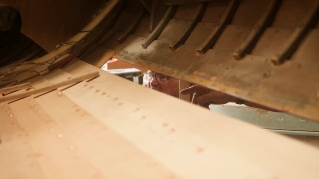 Shipwright and apprentice repairing clinker sailing boat