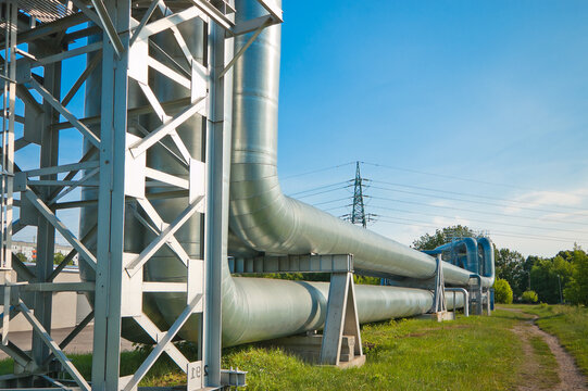 The photo shows a pipeline against a blue sky with green grass in the foreground