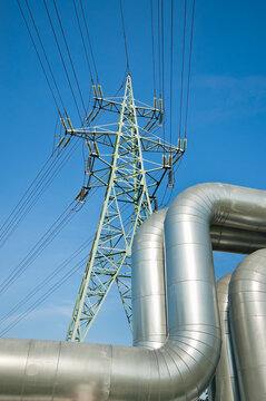 The photo shows a pipeline and a power transmission tower against a blue sky