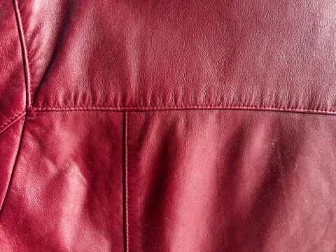 Detail of a red leather jacket featuring neat stitching and texture.