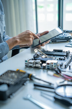 Asian IT engineer man using tablet AI helping fixing mainboard