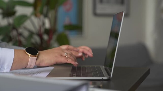 The hands of an adult woman over 40 type on a laptop. The fingers type on the keyboard.