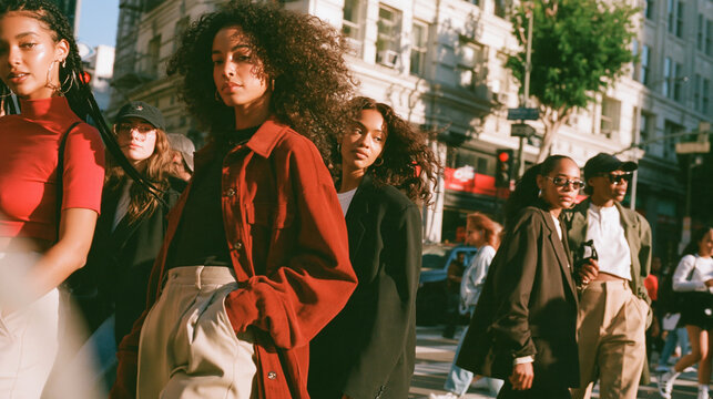Urban Style Ensemble: A group of stylish young individuals, exuding urban chic, stride confidently across a sun-drenched city street, a vibrant tapestry of modern fashion and metropolitan life.