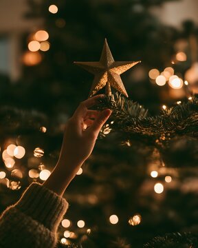 POV Hand Placing Star Topper on Christmas Tree.