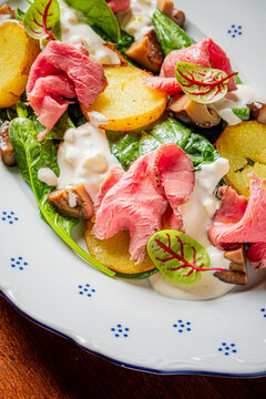 Delicious salad topped with flavorful meats and fresh greens served on a beautifully arranged plate