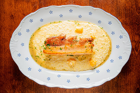Delicious plate of grilled meat served over creamy grits with fresh herbs and garnishes