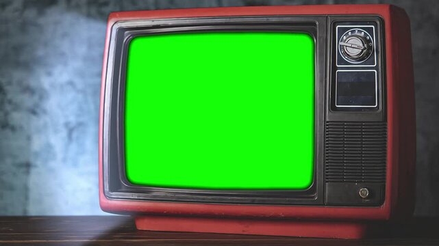 Three old retro tvs with green screens on a wooden table indoors