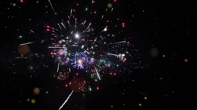 Vibrant fireworks exploding in the night sky with colorful sparks and glowing embers flying everywhere