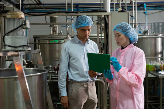 Food scientist man and woman worker inspecting work at food production factory plant.