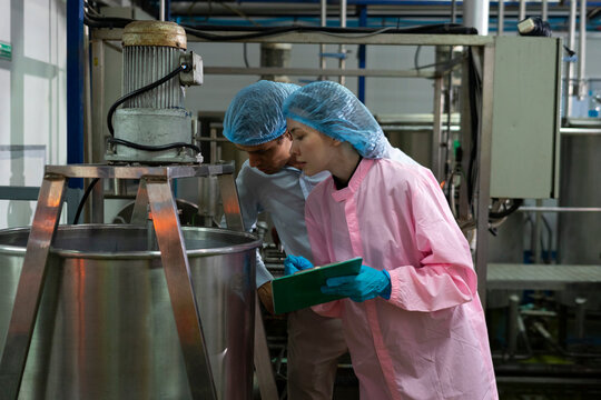 Food scientist man and woman worker inspecting work at food production factory plant.
