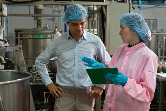 Food scientist man and woman worker inspecting work at food production factory plant.