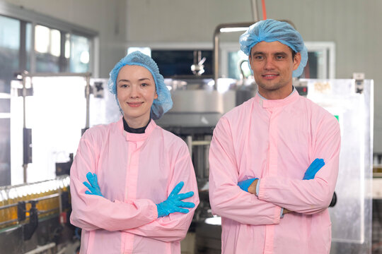 Portrait of two young workers standing with clipboard and laptop in factory, quality control officer in beverage production line factory.