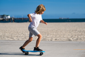 Child with a skateboard in summer. Active child riding skateboard outdoors. Child in sneakers on skateboard. Young child riding skateboard. Kid skateboarding in a T-shirt. Sports activities for kids. © Volodymyr