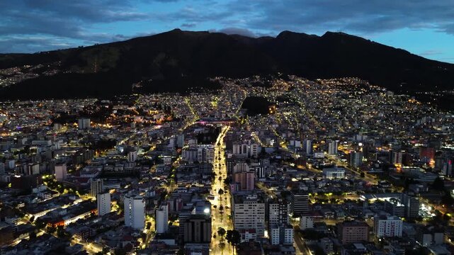 Night Aerial View of Quito Ecuador City Below Dark Mountain Ridge, Dense Urban Lights, High Rise Buildings and South American Capital Skyline