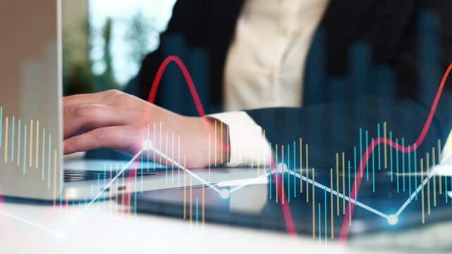 A person is using a laptop in an office. Data graphs appear on the screen. The setting suggests focus on analysis and business work. The time is likely during a regular workday.