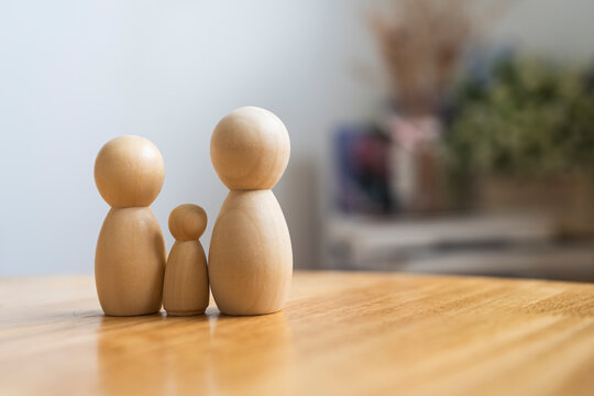 Family planning and parenthood concept with three wooden peg doll figures of parents and child standing on table with copy space for domestic life insurance, youth welfare and healthcare.