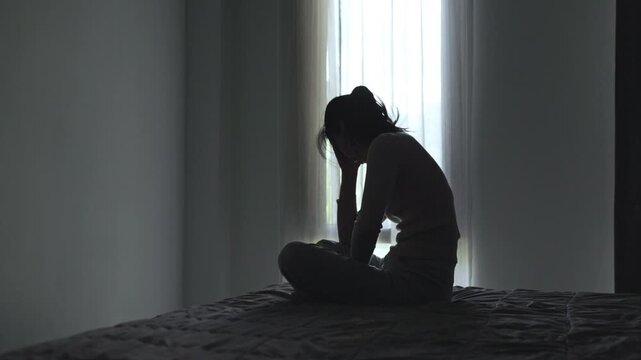 Lonely woman silhouette in a dark room, expressing fear, isolation, emotional pain, and the need for compassionate care.