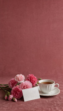 Mothers Day carnations and teacup vertical on dark background with copy space