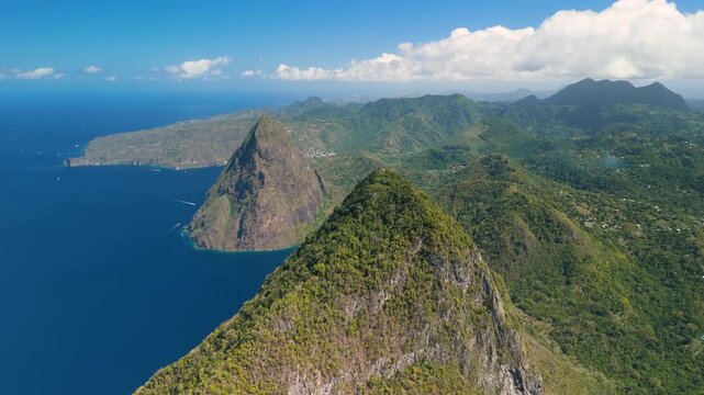 Slow panning aerial shot reveals Petit Piton and Gros Piton with coastal village nestled between twin peaks