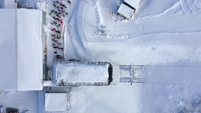 Aerial view of queue for ski lift at snowy winter resort. People in colorful gear waiting at the slope. Perfect for themes of skiing, tourism, winter sports, and mountain lifestyle.