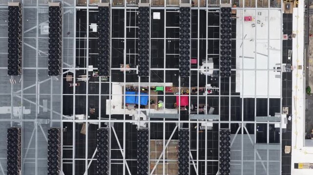 Steel roof framing and installed cooling units form a grid at a Lancaster, Pennsylvania data center build, a crawler crane working the open edge. Aerial top down