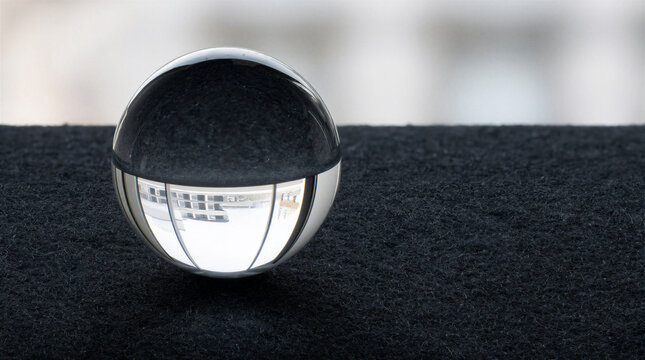 Glass sphere resting on charcoal felt surface with window light refraction showing inverted interior reflection