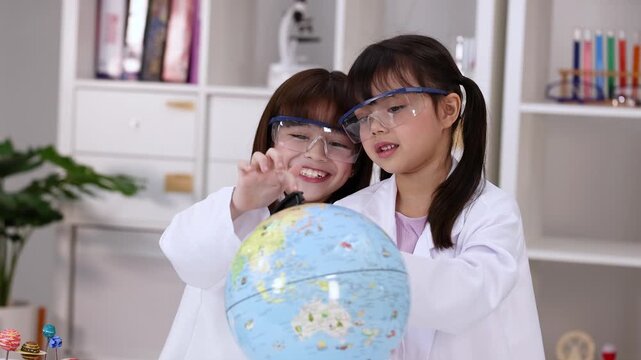 Two Young Girls in Lab Coats Studying a World Globe