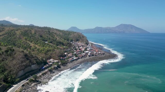 Aerial view of scenic coastal road and black sand beach with turquoise sea in Ende, East Nusa Tenggara, Indonesia.