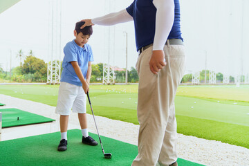 Obraz premium Golf instructor teaching basic stance and setup to young Asian boy