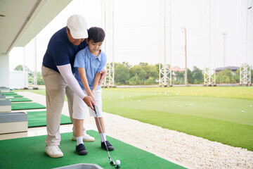 Obraz premium Golf instructor teaching basic stance and setup to young Asian boy