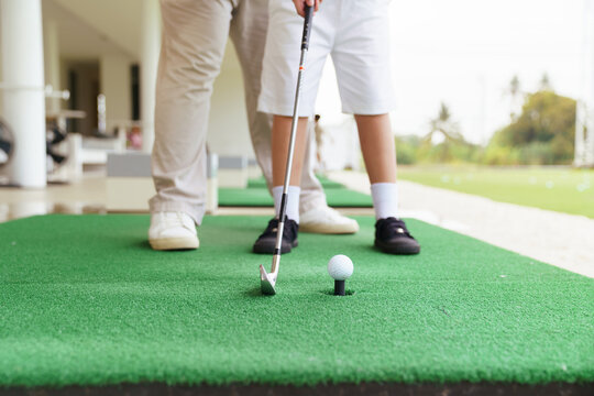 Professional golf coach guiding young student ball address position