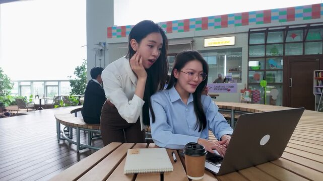 Two Happy Asian Businesswomen Working on Laptop in Bangkok Office