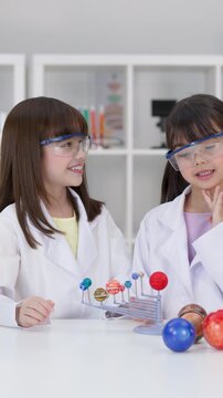 Elementary Students in Lab Coats Studying Solar System Model