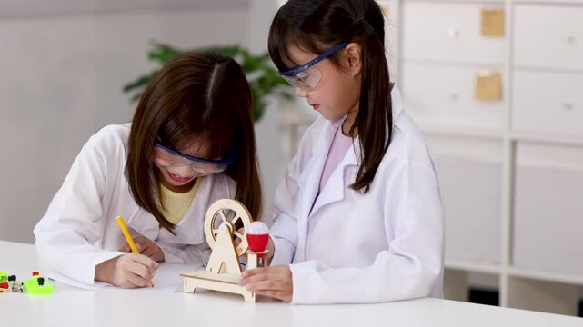 Asian Students in Lab Coats Conducting Science Experiment with Wooden Wheel