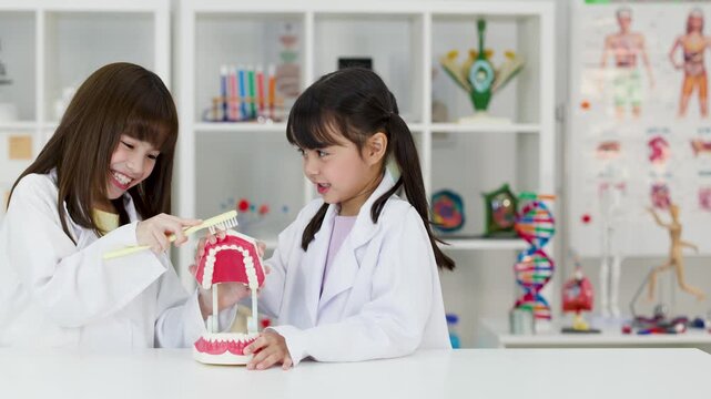 Two Young Students in Lab Coats Practicing Dental Hygiene with Model