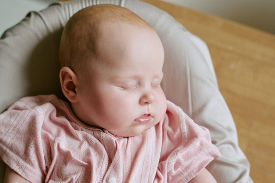 Caucasian baby sleeping peacefully in bouncer seat at home. Close up shot suitable for pediatric healthcare marketing, infant sleep consulting, parenting blogs and baby care product campaigns